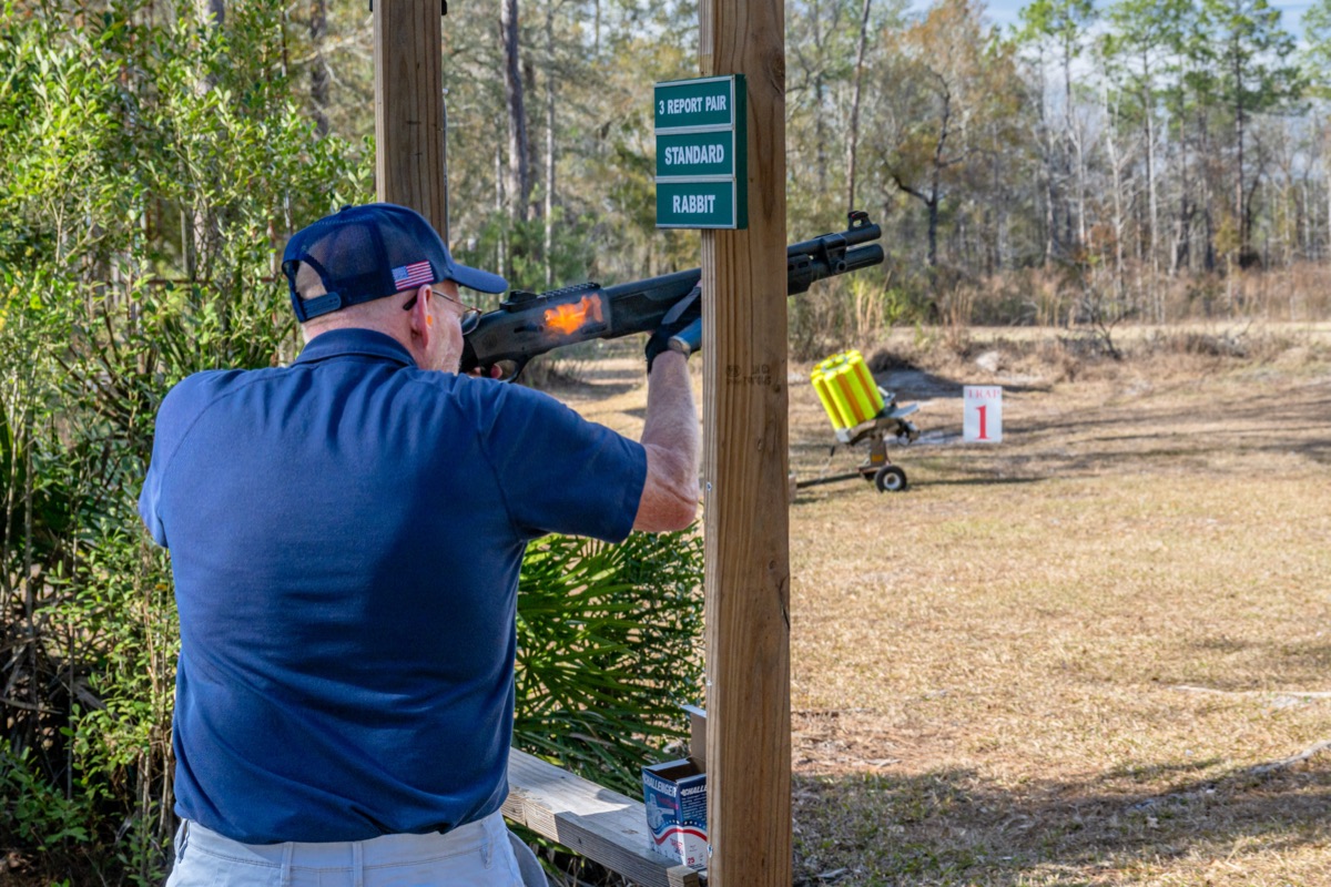 A shooter breaking clays at an outdoor sporting station
