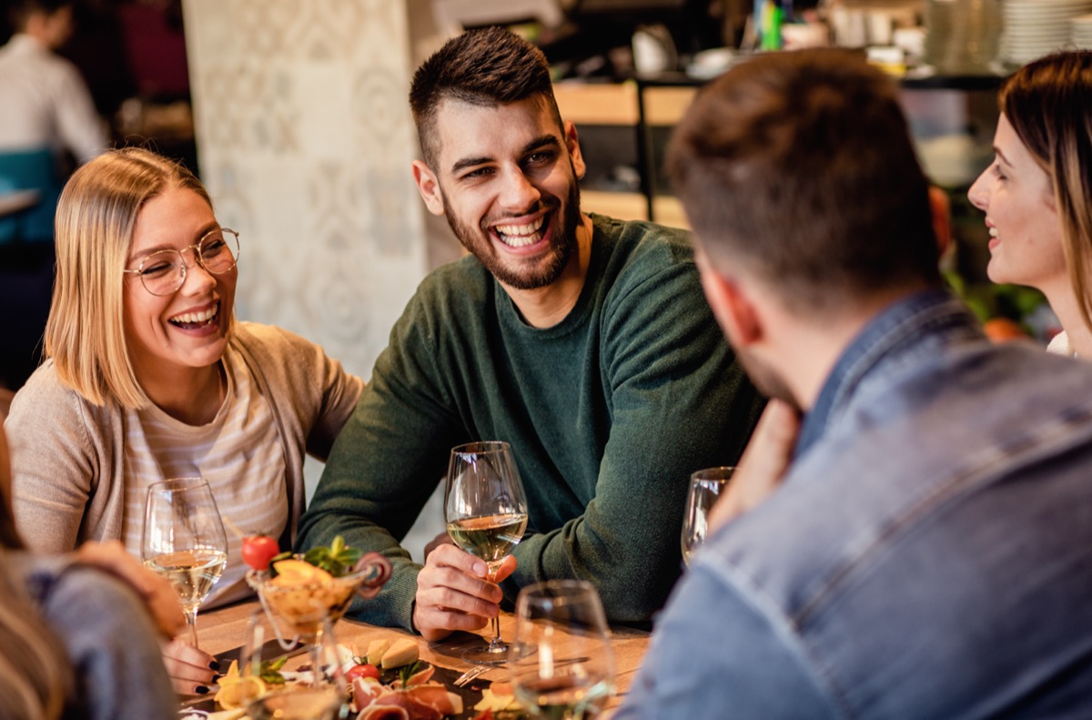 Friends laughing over a shared meal at a restaurant table