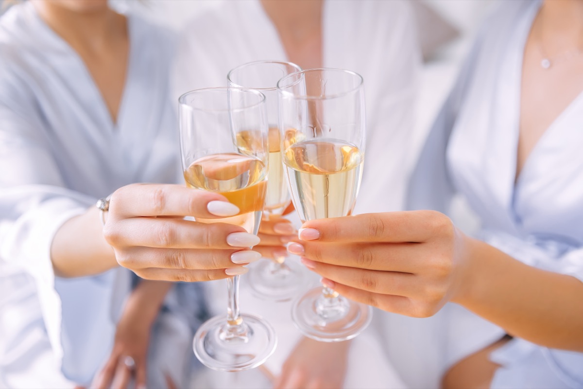 Bridesmaids clinking champagne glasses while getting ready