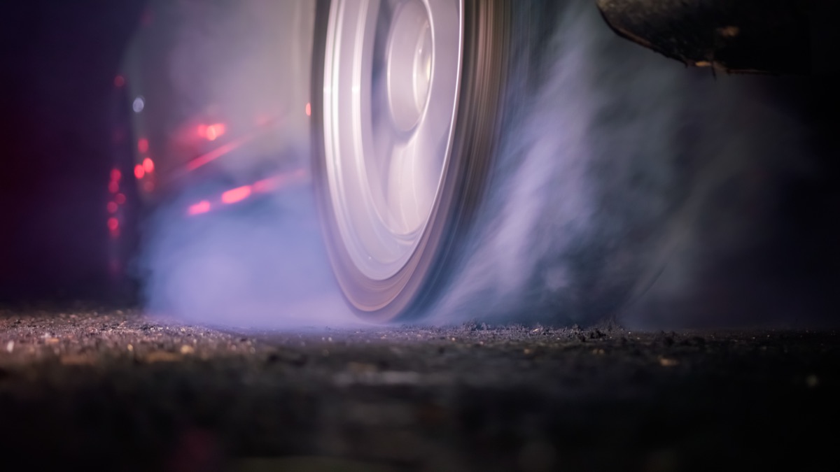 A race car wheel spinning in smoke under night lights