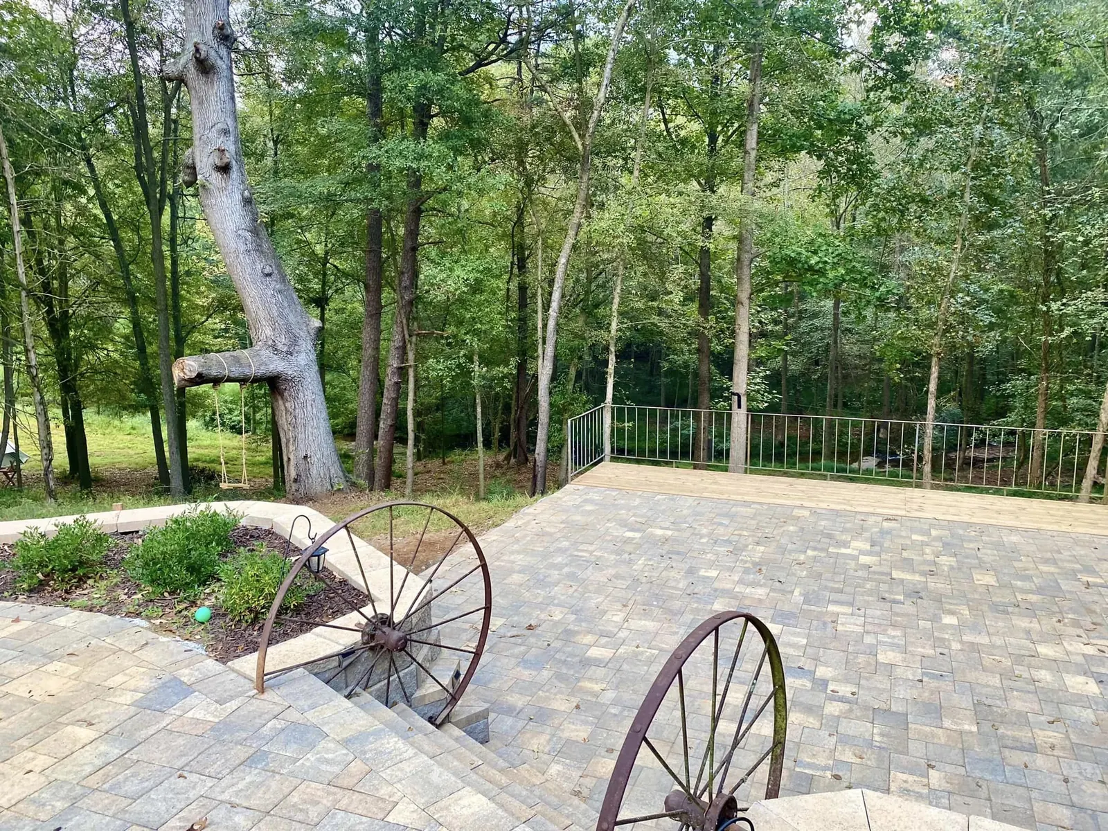 Creekside terrace with iron wagon wheels and trees at The Shed at Papa's Creek, Lavonia Georgia