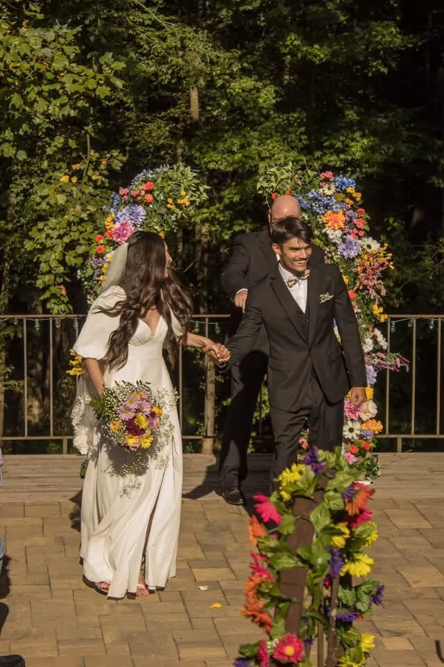 Couple recessional through colorful floral arch on terrace at The Shed at Papa's Creek, Lavonia Georgia