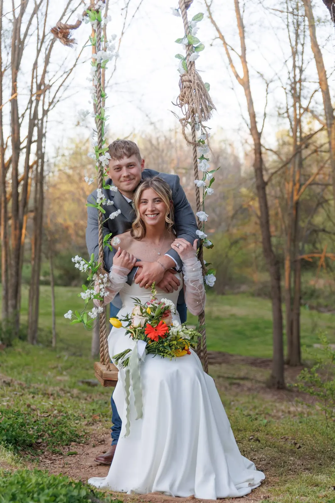 Bride and groom full-length portrait on the rope swing – colorful bouquet, forest behind, Lavonia Georgia