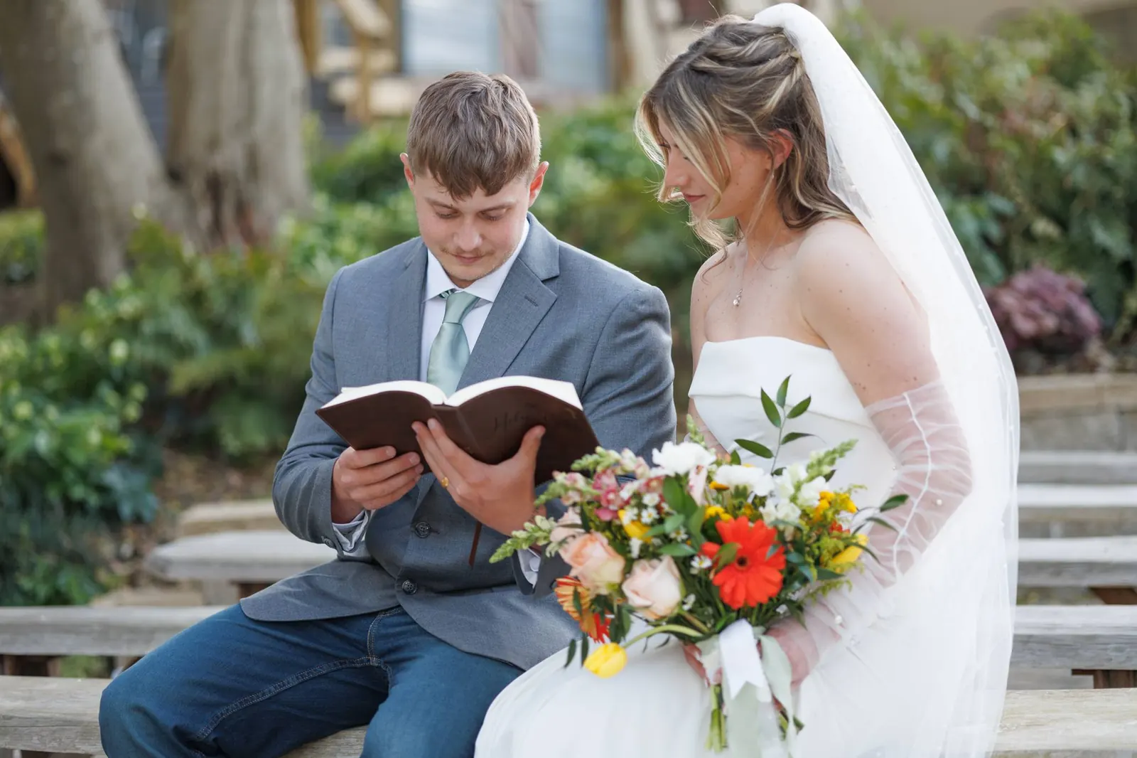Groom reading from the Bible to bride on ceremony terrace bench at The Shed at Papa's Creek, Lavonia Georgia