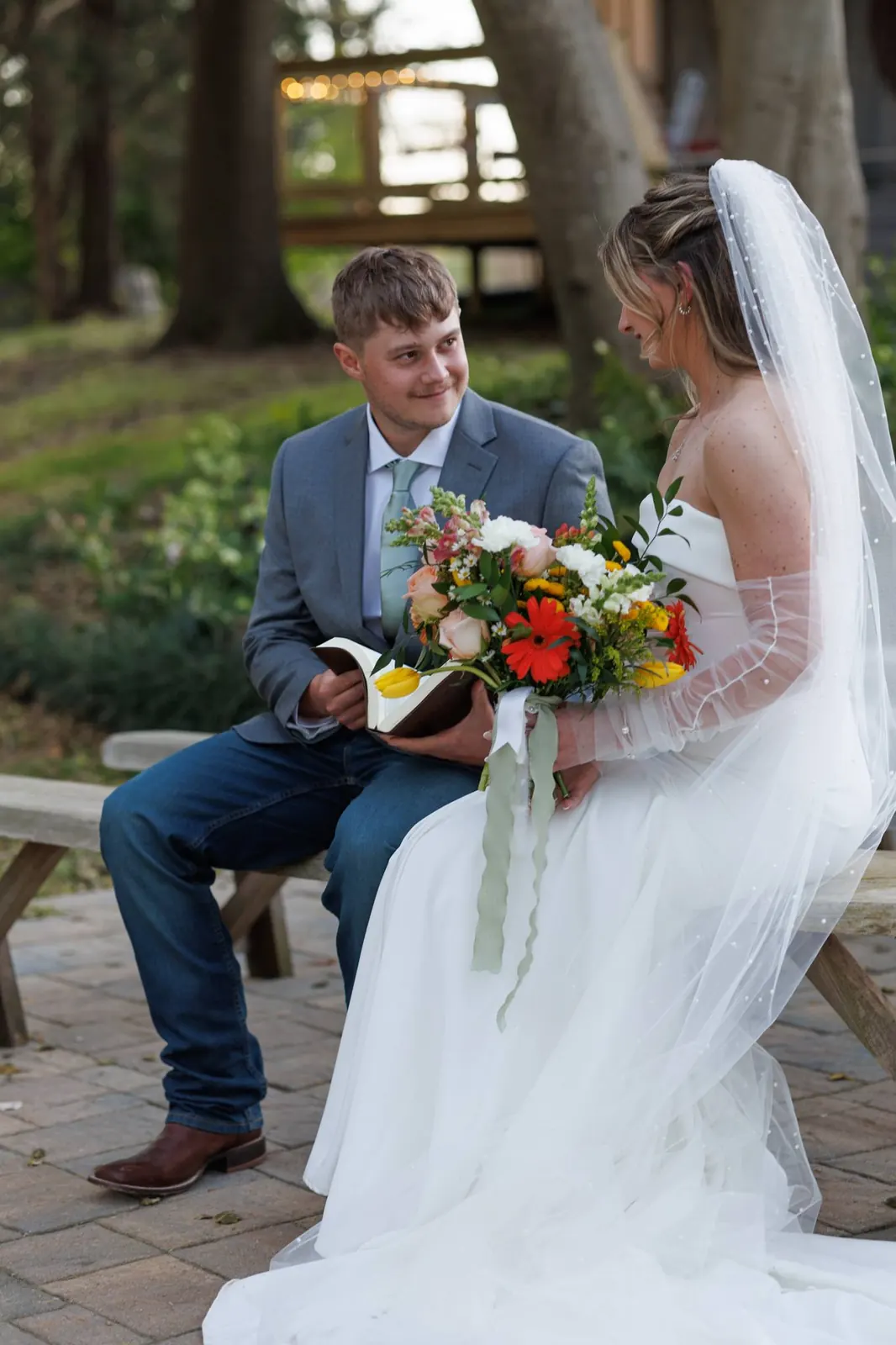 Bride and groom on terrace bench – groom with Bible, smiling at bride, The Shed at Papa's Creek, Lavonia Georgia
