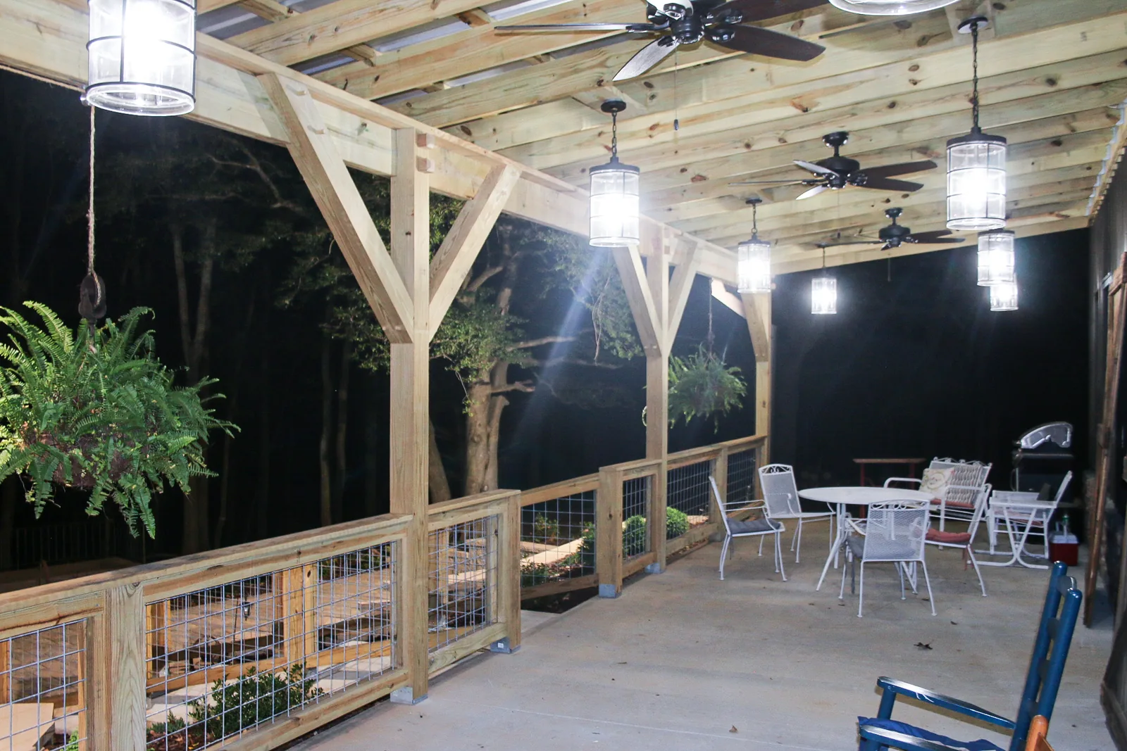 The covered porch glowing at night with café tables ready for guests