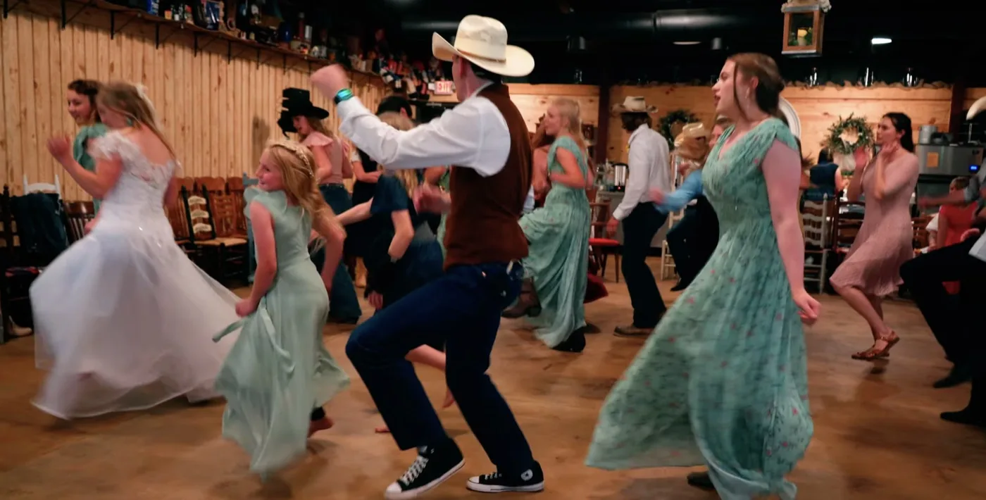 Wedding party and guests filling the dance floor inside The Shed