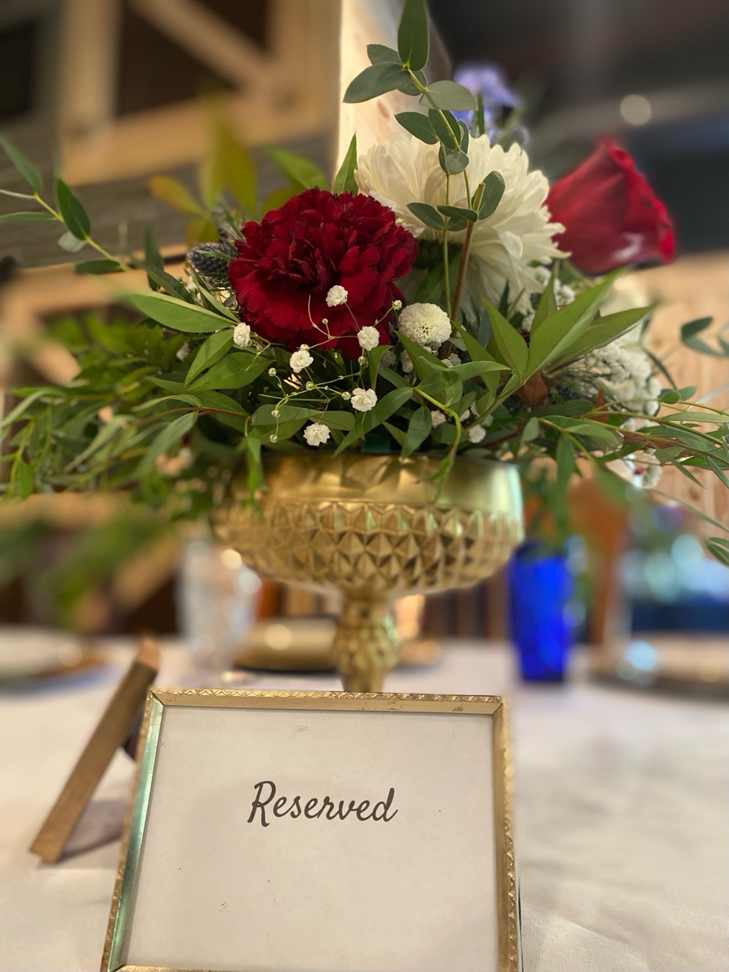 Gold vessel filled with greenery and flowers on a guest table